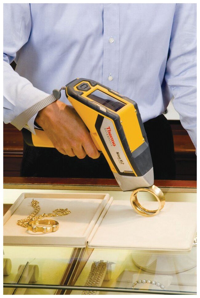 Employee using handheld Niton Precious Metals XRF Analyzer for elemental analysis of gold jewelry