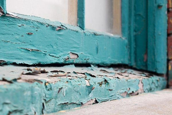 Chipped blue lead paint on the window sill of an industrial facility